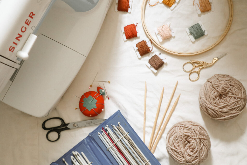 Craft supplies. Sewing machine, crochet hooks, yarn, embroidery, cross stitching, and knitting